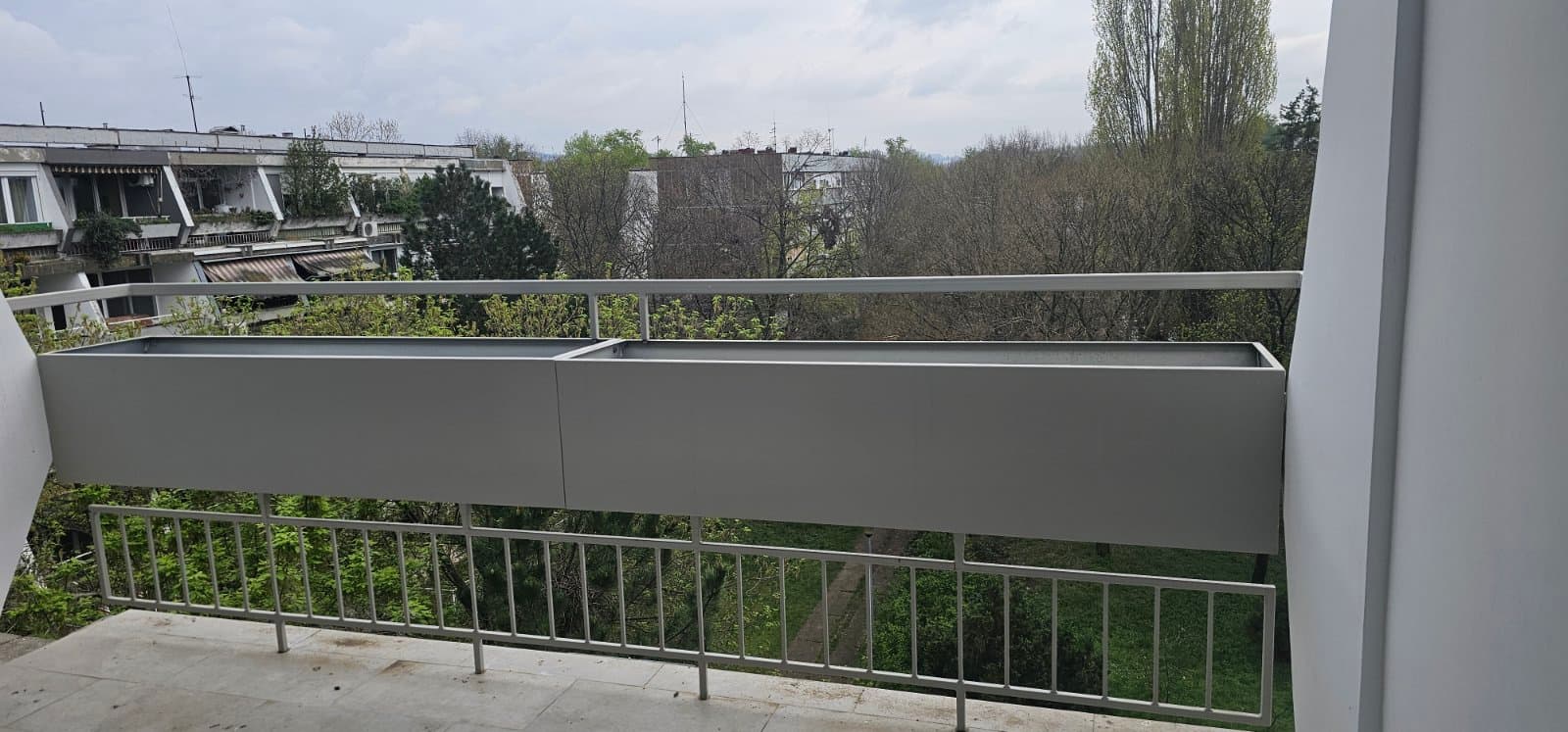 Sive metalne žardinjere okačene na ogradu terase