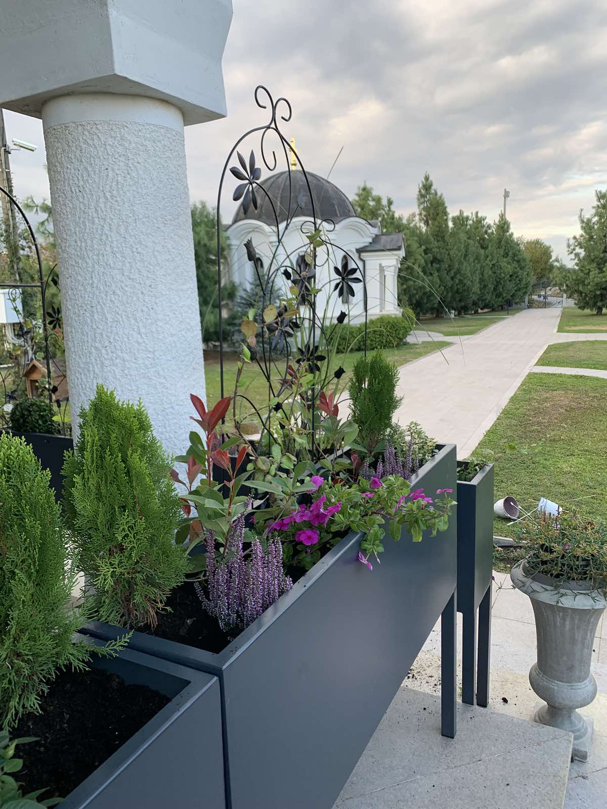 Metalne žardinjere na tremu dvorišta sa pogledom na kapelu sa kupolom